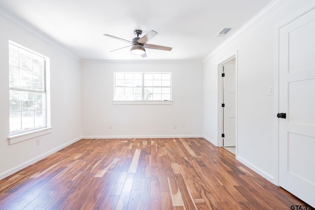 empty room with ceiling fan, plenty of natural light, wood-type flooring, and crown molding