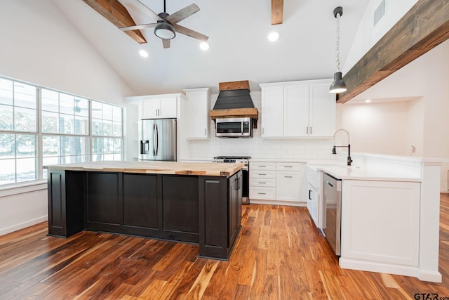 kitchen with white cabinets, custom range hood, hanging light fixtures, and stainless steel appliances