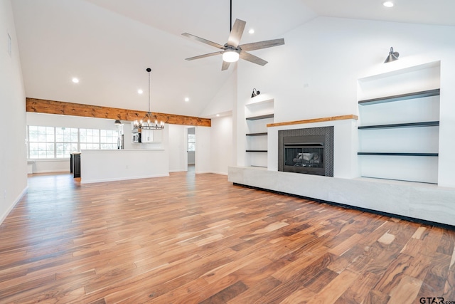 unfurnished living room with built in features, light hardwood / wood-style floors, ceiling fan with notable chandelier, and high vaulted ceiling