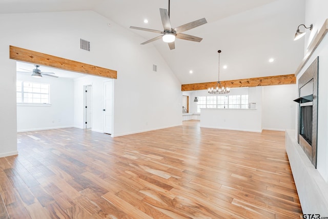 unfurnished living room featuring high vaulted ceiling, light wood-type flooring, and ceiling fan with notable chandelier