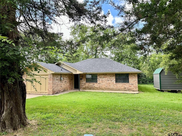 ranch-style house featuring a shed, a garage, and a front lawn