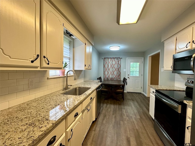 kitchen featuring backsplash, light stone countertops, sink, and appliances with stainless steel finishes