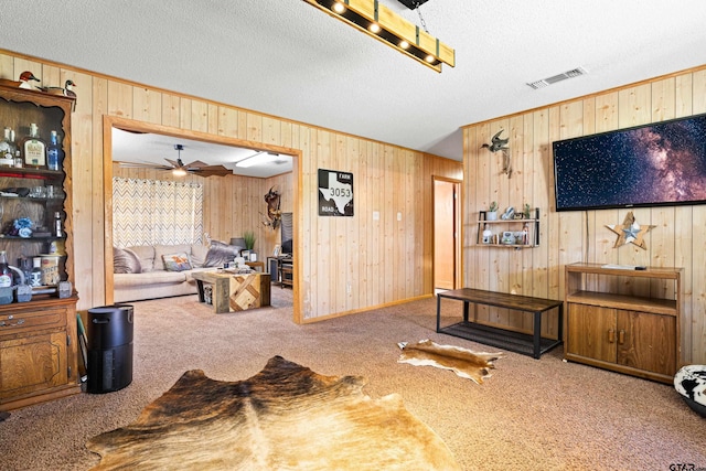 10929 County Road 41, Tyler, TX 75706 - living room with wooden walls, carpet flooring, a ceiling fan, a textured ceiling, and ornamental molding