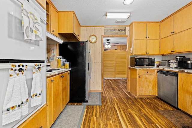 10929 County Road 41, Tyler, TX 75706 - kitchen featuring appliances with stainless steel finishes, a textured ceiling, a ceiling fan, wooden walls, and dark wood finished floors