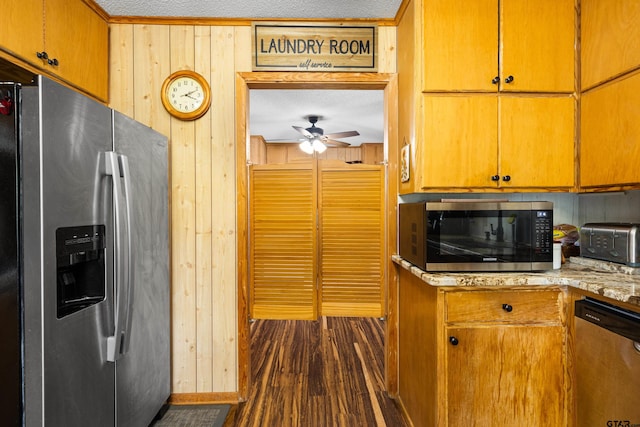 10929 County Road 41, Tyler, TX 75706 - kitchen featuring stainless steel appliances, a ceiling fan, wood walls, and dark wood-type flooring