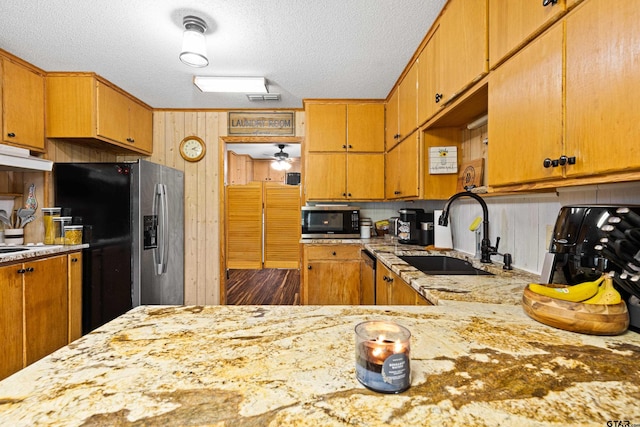 10929 County Road 41, Tyler, TX 75706 - kitchen with appliances with stainless steel finishes, a textured ceiling, light stone countertops, under cabinet range hood, and wooden walls