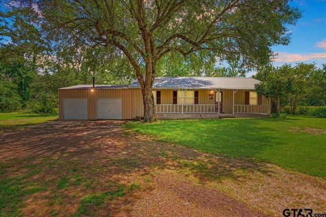 3268 Farm Rd Unit 1487, Bogata, TX 75417 - ranch-style house featuring covered porch, a front yard, and an attached garage