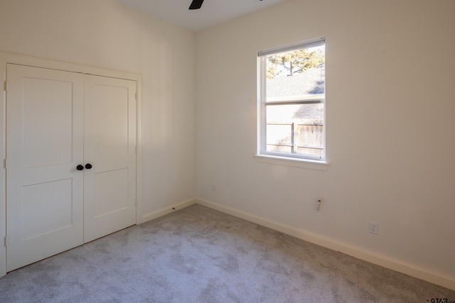 unfurnished bedroom featuring ceiling fan, light carpet, and a closet