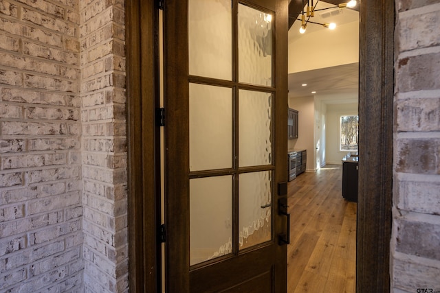 corridor featuring a chandelier, light hardwood / wood-style floors, and brick wall