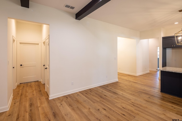 unfurnished living room with beamed ceiling, light wood-type flooring, and a notable chandelier