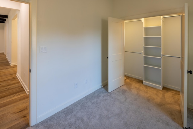 unfurnished bedroom with light carpet and a closet