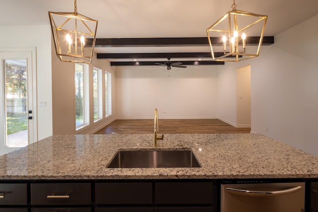 kitchen featuring light stone countertops, dishwasher, sink, hanging light fixtures, and ceiling fan with notable chandelier