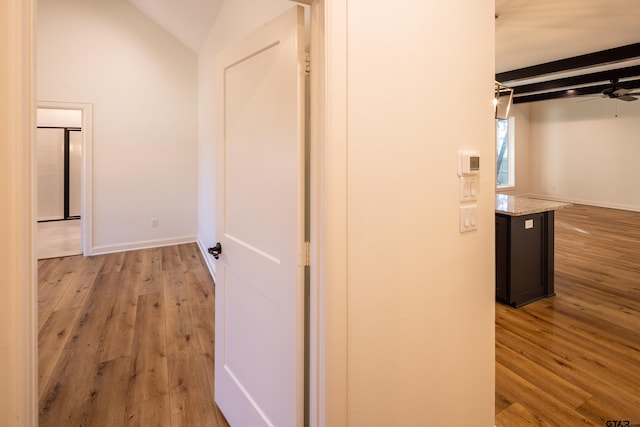 corridor with vaulted ceiling with beams and light wood-type flooring