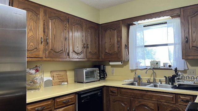 kitchen with dishwasher, sink, stainless steel fridge, dark brown cabinetry, and a textured ceiling