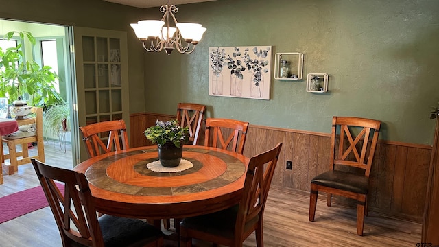 dining space featuring a chandelier, light hardwood / wood-style flooring, and wood walls