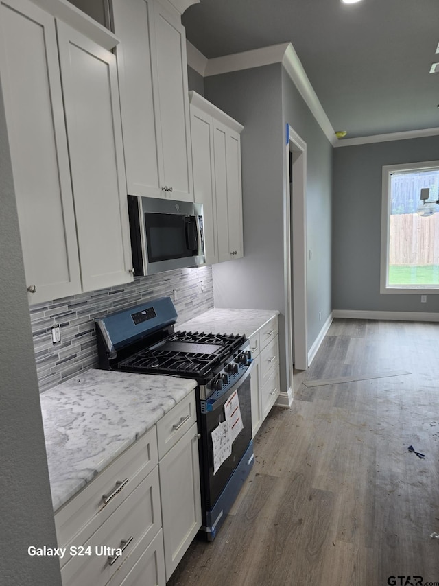 913 Alex Dr, Whitehouse, TX 75791 - kitchen featuring stainless steel microwave, black range with gas stovetop, wood finished floors, white cabinetry, and decorative backsplash