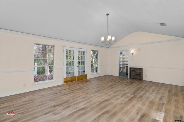 unfurnished living room featuring french doors, a chandelier, light wood-type flooring, and plenty of natural light