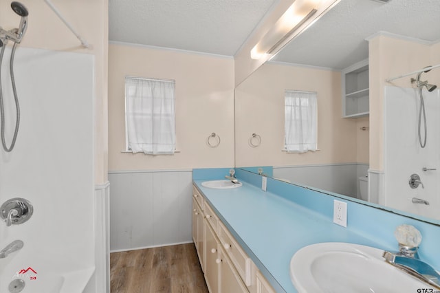 bathroom with hardwood / wood-style floors, washtub / shower combination, crown molding, vanity, and a textured ceiling