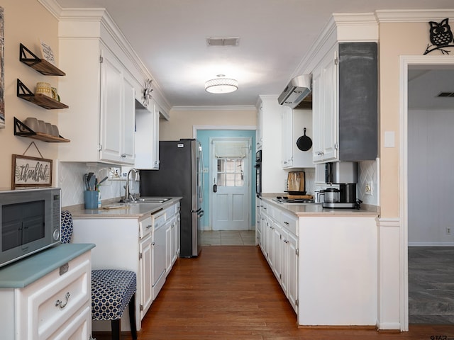 kitchen featuring wall chimney exhaust hood, ornamental molding, appliances with stainless steel finishes, and white cabinets