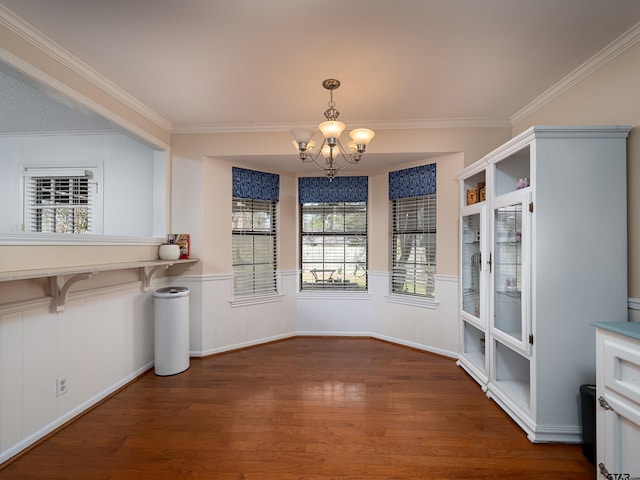 unfurnished dining area with crown molding, wood-type flooring, and a chandelier