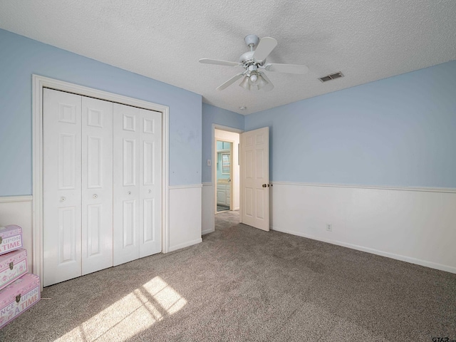 unfurnished bedroom featuring ceiling fan, carpet flooring, a textured ceiling, and a closet