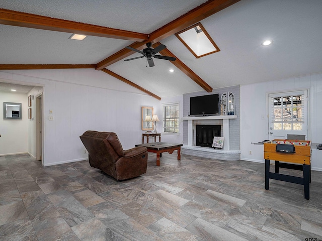 living room featuring a brick fireplace, vaulted ceiling with skylight, a healthy amount of sunlight, and ceiling fan