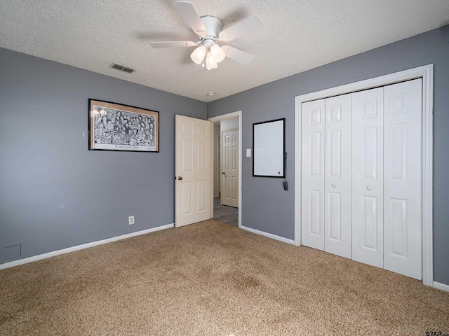 unfurnished bedroom with ceiling fan, carpet, a textured ceiling, and a closet