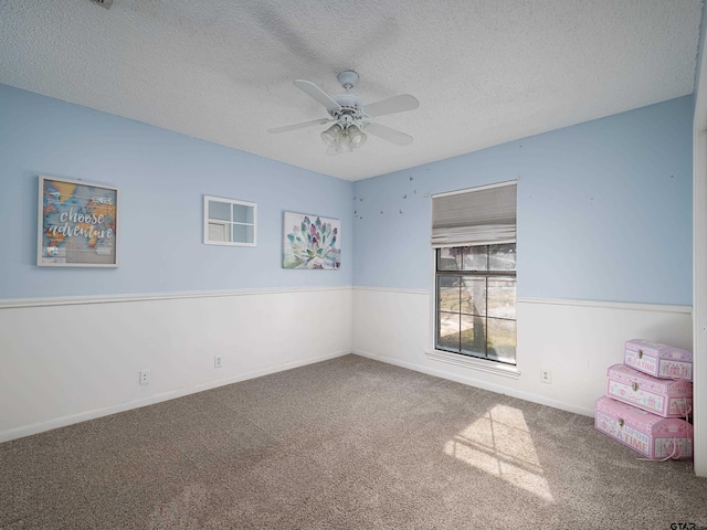 carpeted spare room featuring ceiling fan and a textured ceiling