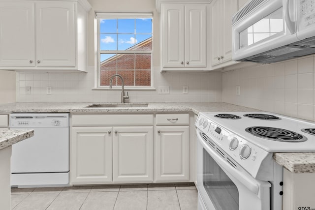 kitchen featuring sink, tasteful backsplash, light tile patterned floors, white appliances, and white cabinets