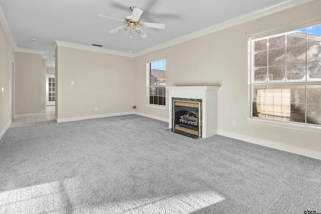 unfurnished living room with ceiling fan, carpet flooring, crown molding, and plenty of natural light