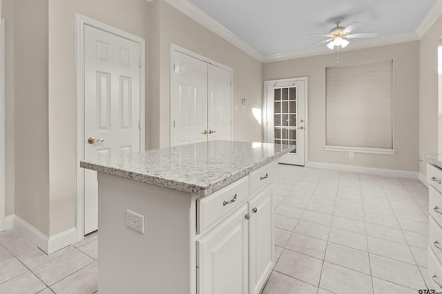 kitchen featuring light tile patterned flooring, crown molding, a kitchen island, white cabinetry, and ceiling fan