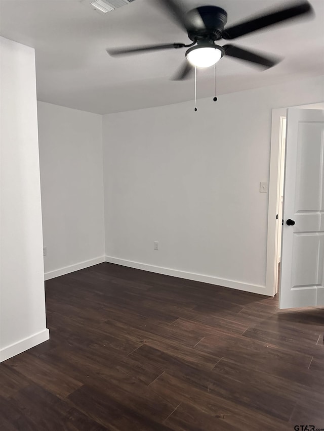 unfurnished room with dark wood finished floors, a ceiling fan, and baseboards