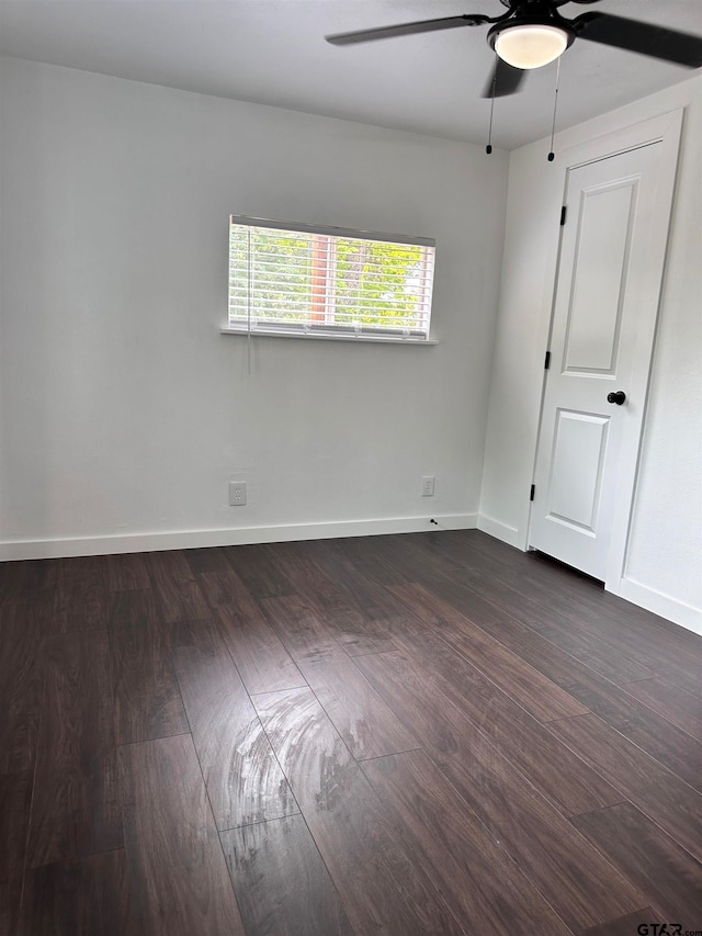 unfurnished room featuring dark wood finished floors, a ceiling fan, and baseboards