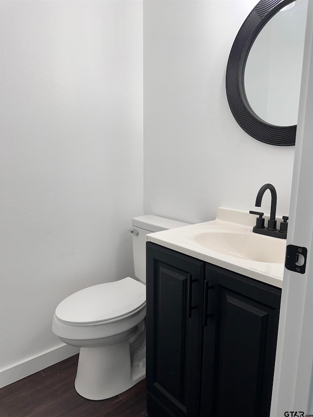 bathroom with vanity, wood finished floors, toilet, and baseboards