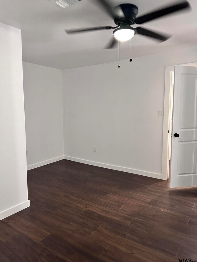 spare room featuring dark wood-style floors, ceiling fan, and baseboards