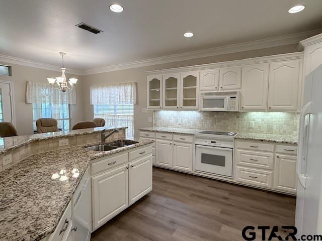 kitchen featuring white appliances, sink, pendant lighting, a notable chandelier, and white cabinetry