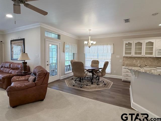 dining space with dark hardwood / wood-style floors, ceiling fan with notable chandelier, and ornamental molding