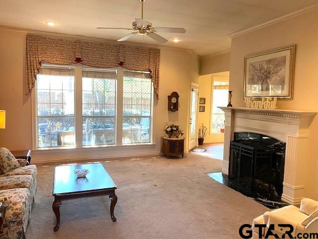 carpeted living room featuring ceiling fan, ornamental molding, a fireplace with flush hearth, and recessed lighting