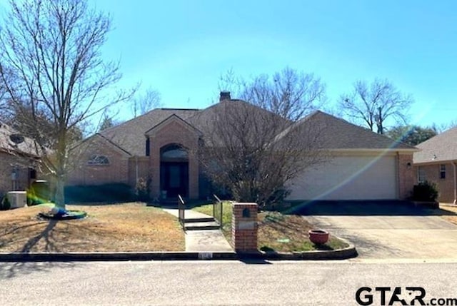 single story home featuring a garage, driveway, a chimney, and central AC unit