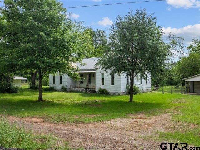 exterior space with a porch, fence, a front yard, and a detached garage