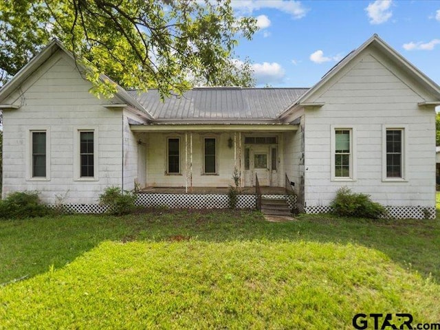 rear view of house featuring covered porch, a yard, and metal roof