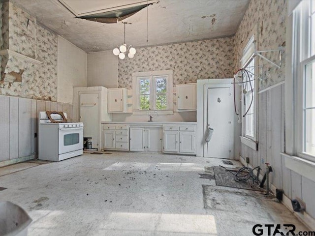 kitchen featuring white cabinets, hanging light fixtures, a notable chandelier, light countertops, and white range with gas cooktop