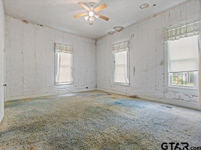 empty room featuring carpet floors, ceiling fan, and plenty of natural light