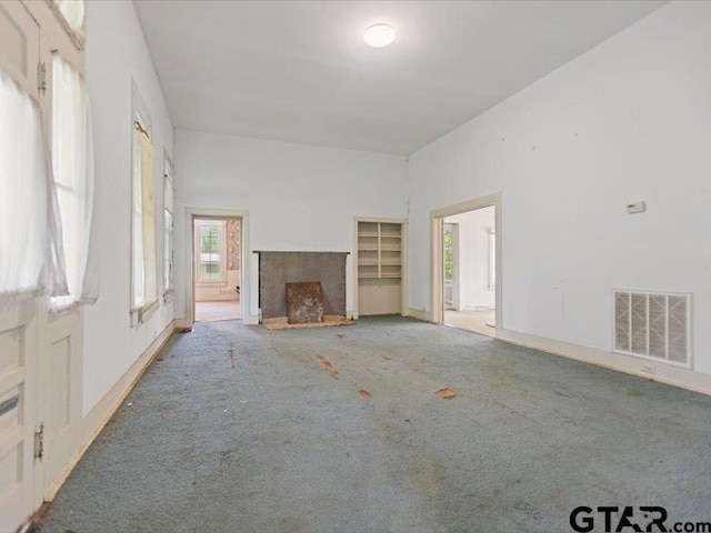 unfurnished living room featuring a fireplace, baseboards, carpet, and visible vents