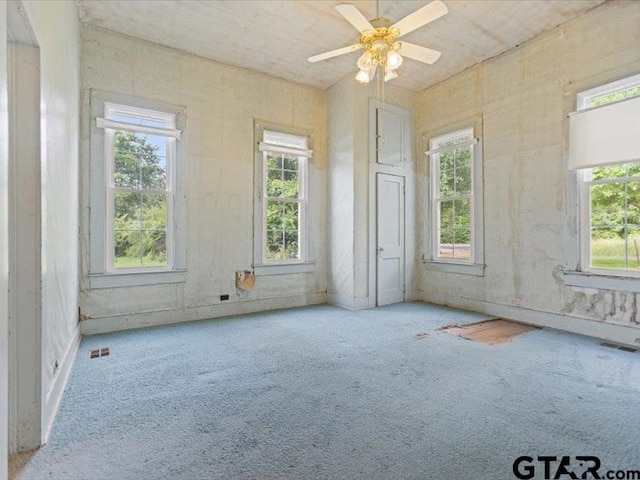 carpeted spare room featuring a healthy amount of sunlight and ceiling fan