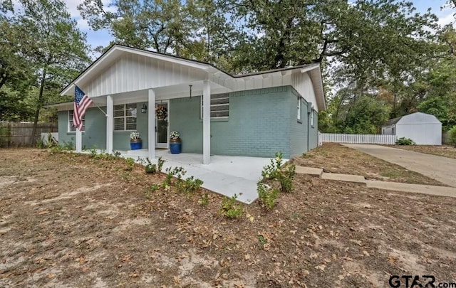 back of house with brick siding, covered porch, and fence