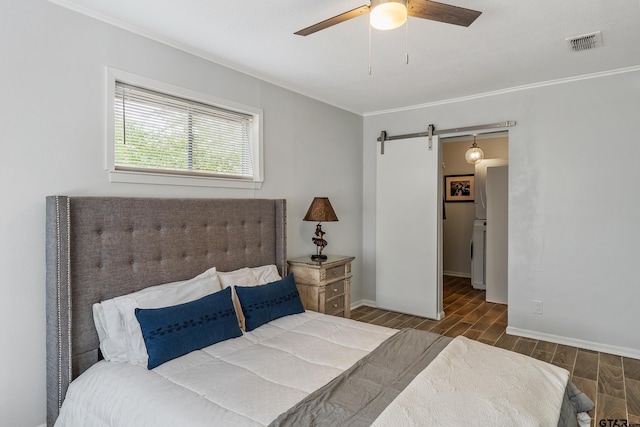 bedroom featuring a barn door, washer / dryer, visible vents, wood tiled floor, and crown molding