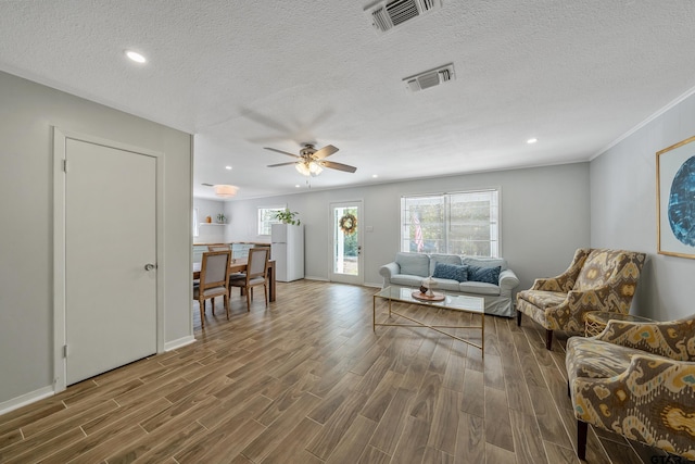 living area featuring visible vents, wood finished floors, and a healthy amount of sunlight