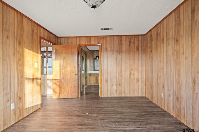 unfurnished room with hardwood / wood-style flooring, a textured ceiling, and wood walls