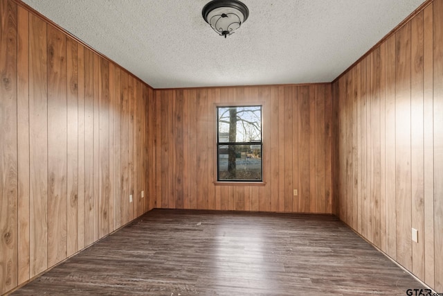 spare room with dark hardwood / wood-style floors, wooden walls, and a textured ceiling